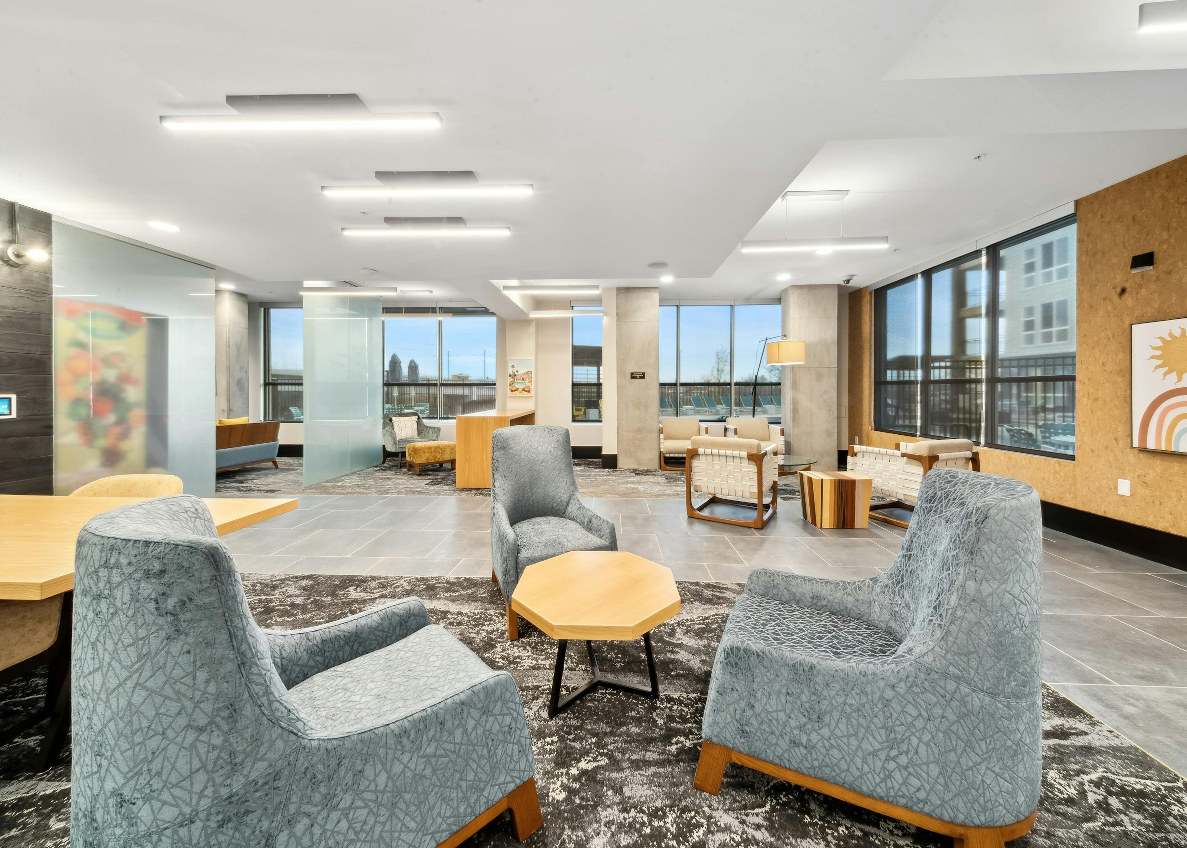 Business center at AMLI RiNo with 3 blue velvet chairs and other seating and tables with a view of pool and skyline