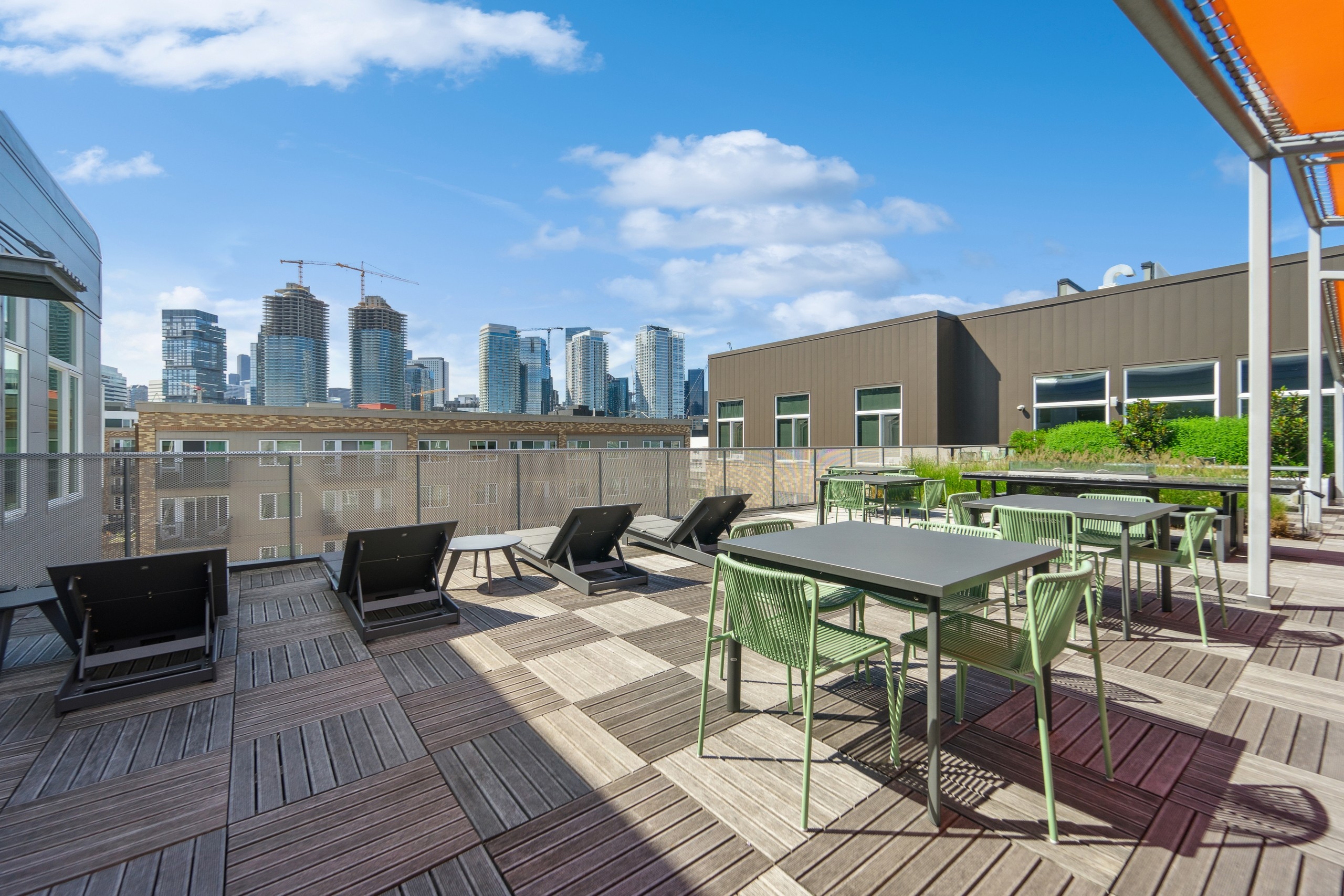 AMLI South Lake Union rooftop with 5 lounge chairs and many silver tables and green chairs overlooking city skyline