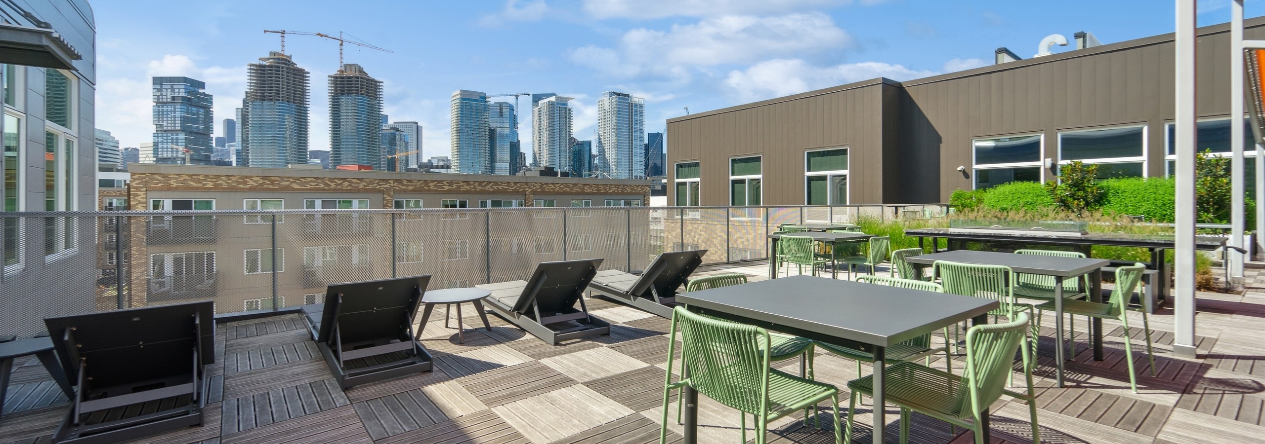 AMLI South Lake Union rooftop with 5 lounge chairs and many silver tables and green chairs overlooking city skyline