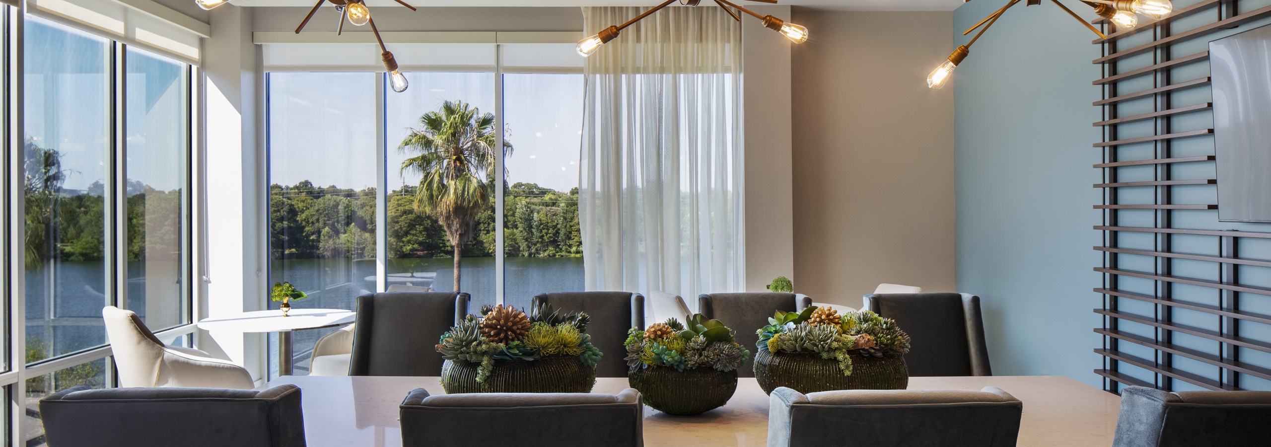 AMLI South Shore resident dining room with wood table and 8 chairs and floor to ceiling windows showcasing Lady Bird Lake
