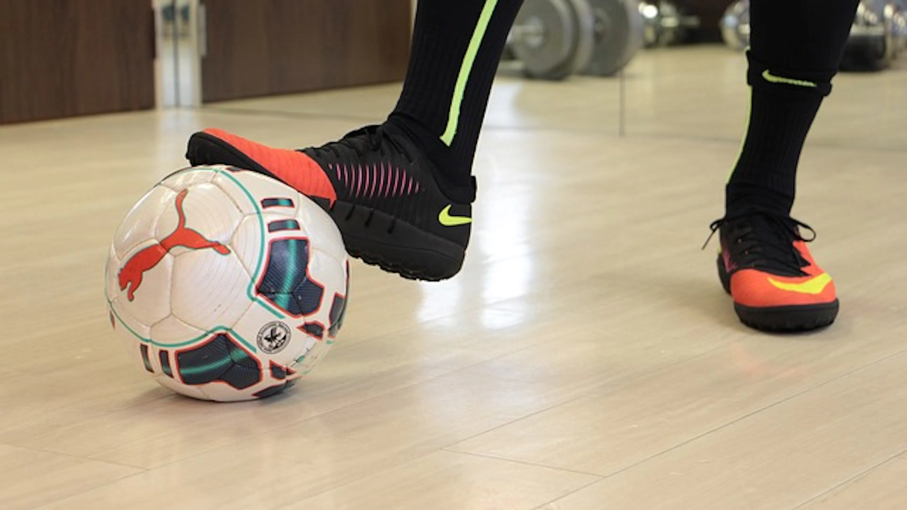 Close up of a futsal soccer ball with a persons foot resting on top of it