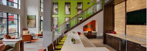 AMLI Ponce Park clubroom with large countertop for entertaining and multiple areas of seating with staircase to upstairs area