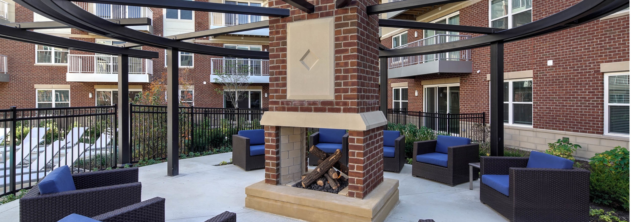 Exterior view of courtyard fireplace with several blue cushioned sitting areas at AMLI Deerfield apartment community