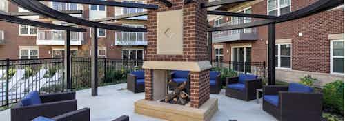 Exterior view of courtyard fireplace with several blue cushioned sitting areas at AMLI Deerfield apartment community