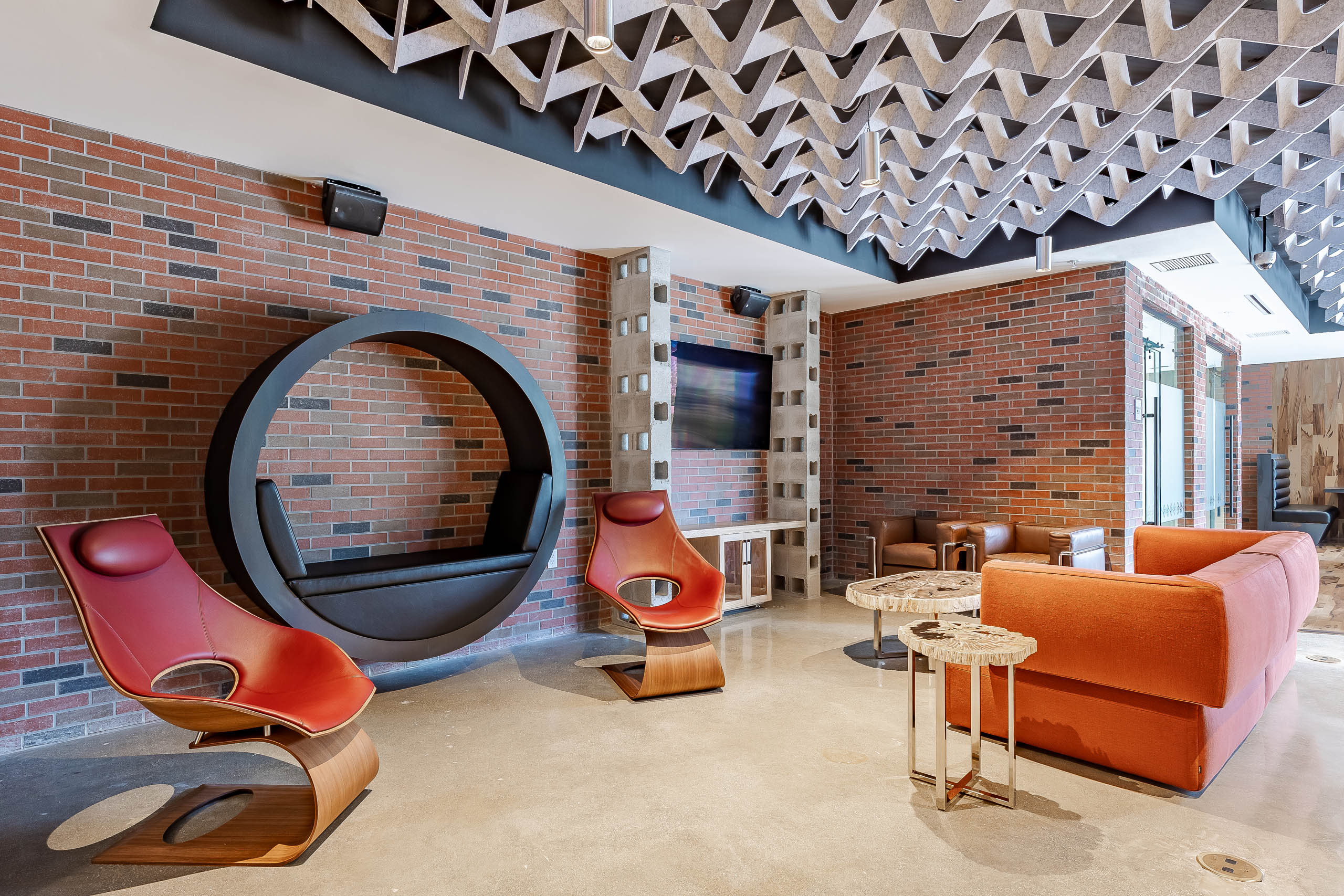 AMLI Midtown Miami apartment amenity space with brick walls and black circular wall mounted chair and TV with seating  