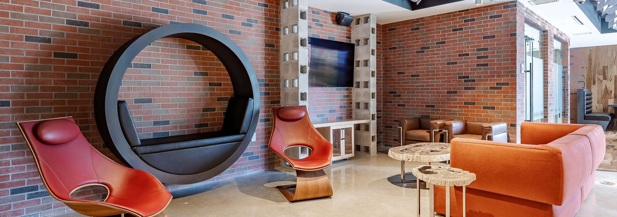 AMLI Midtown Miami apartment amenity space with brick walls and black circular wall mounted chair and TV with seating