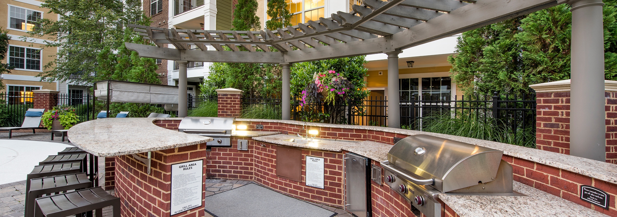 Outdoor kitchen area at AMLI North Point with red brick under white wrap around countertops with a grill and barstools