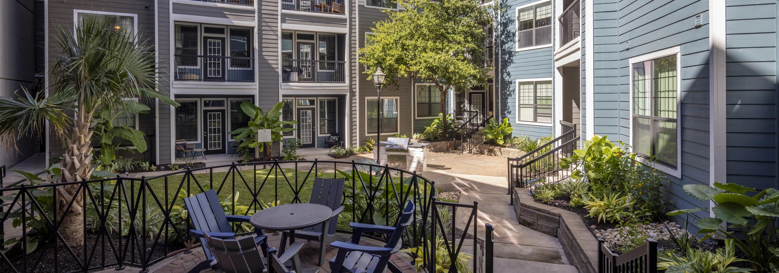 AMLI Eastside courtyard with outdoor seating and grill area surrounded by apartment balconies and lush greenery