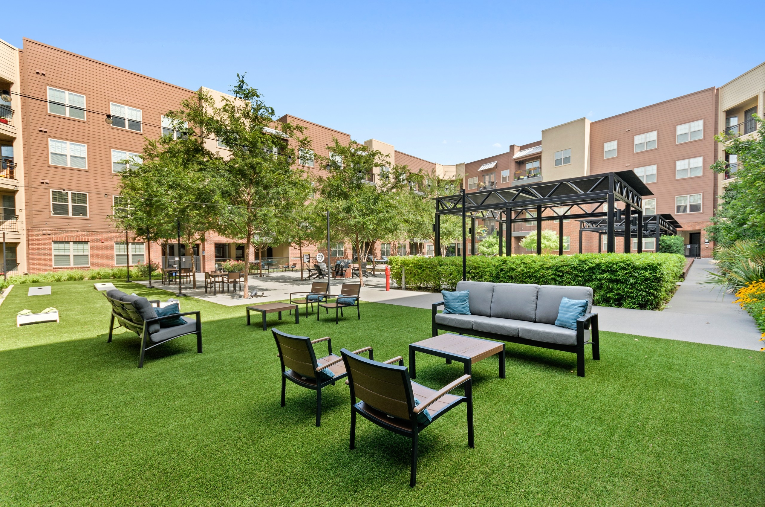 Pristinely landscaped outdoor courtyard at AMLI Grapevine with outdoor games and multiple seating areas shaded by trees