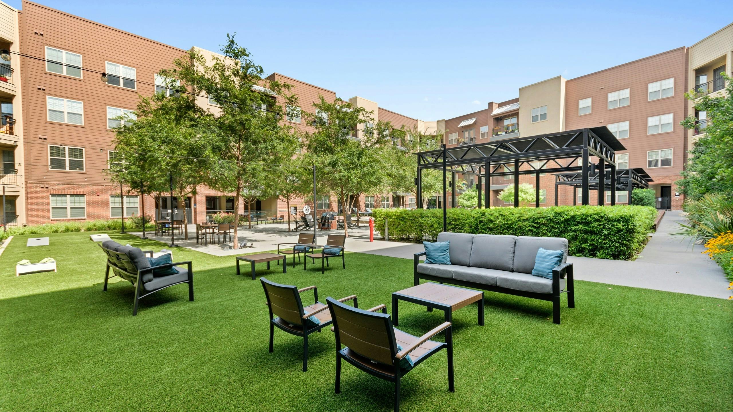 Pristinely landscaped outdoor courtyard at AMLI Grapevine with outdoor games and multiple seating areas shaded by trees