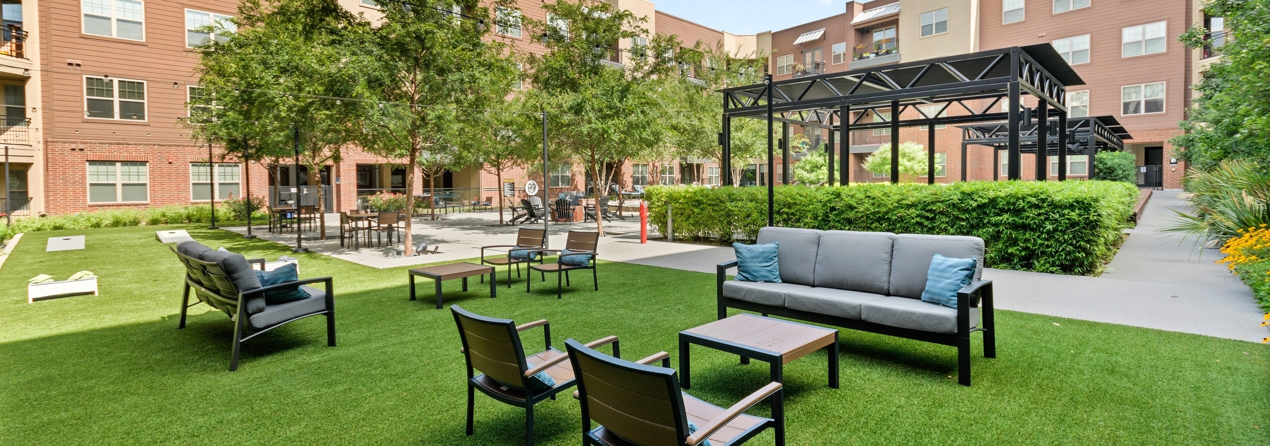 Pristinely landscaped outdoor courtyard at AMLI Grapevine with outdoor games and multiple seating areas shaded by trees