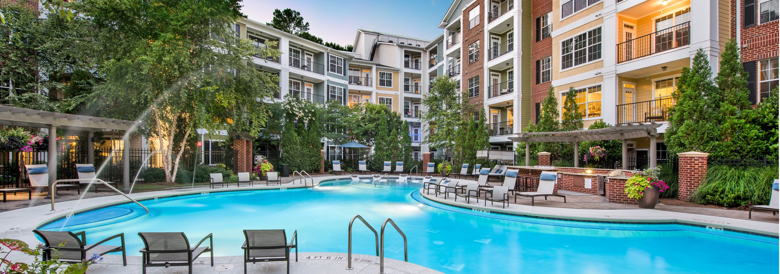 Alternate pool view at AMLI North Point with surrounding lounge chairs and vibrant trees with building facade in the back