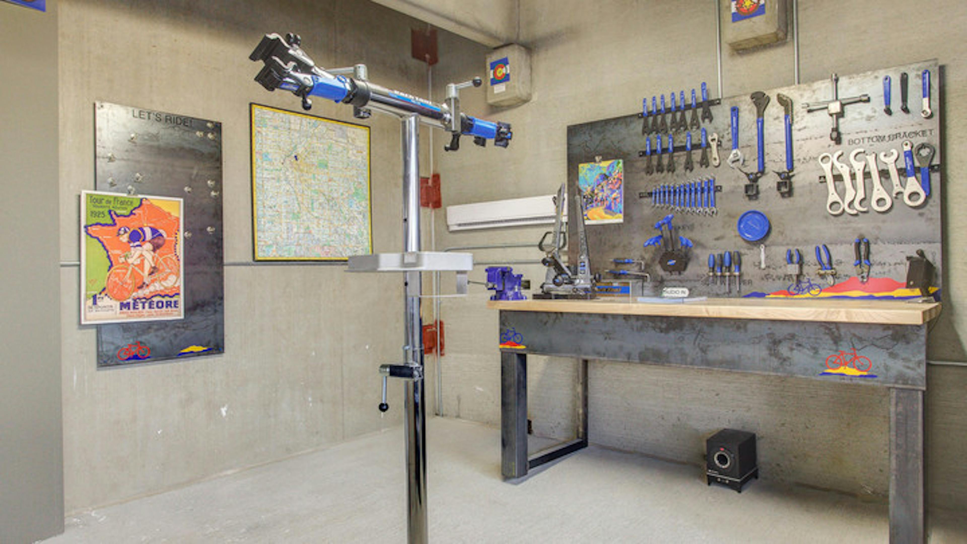 Interior of the bike repair room at AMLI Riverfront Park apartments with a work bench and tools and steel bike repair stand 