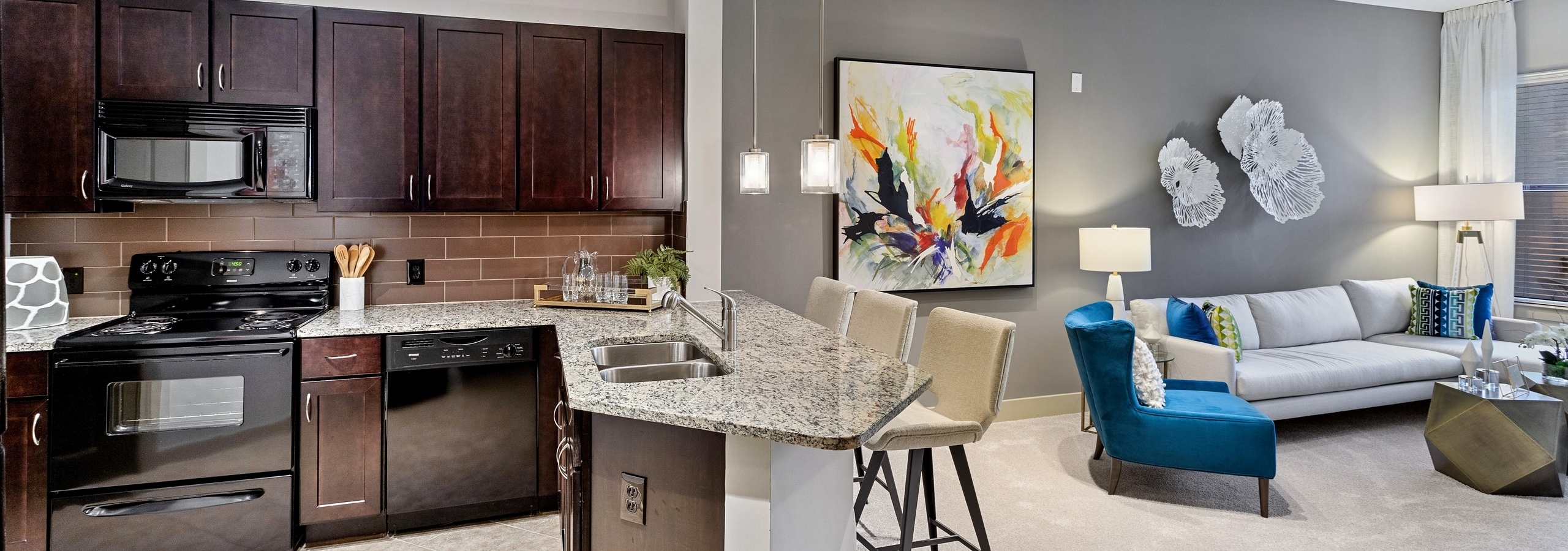 AMLI Parkside apartment kitchen and living area with dark wood cabinets and granite counters and peek into the living area
