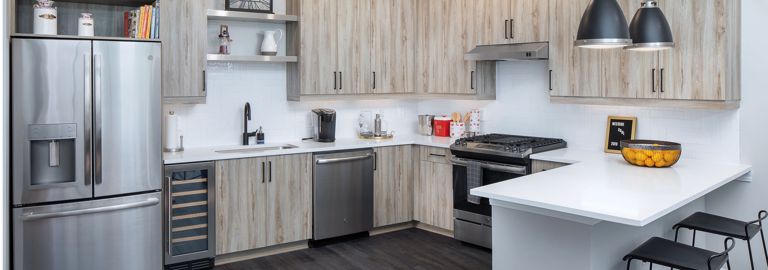 AMLI Westside kitchen with dark wood floors and modern black light fixtures hanging above barstools at counter area
