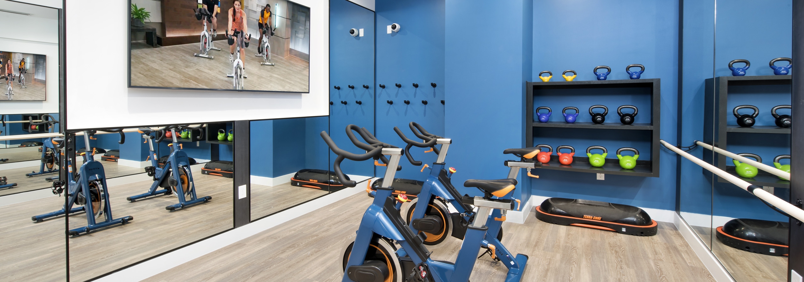 Interior of fitness center at AMLI Decatur with fitness on demand on large screen TV with spin bikes and kettle bells