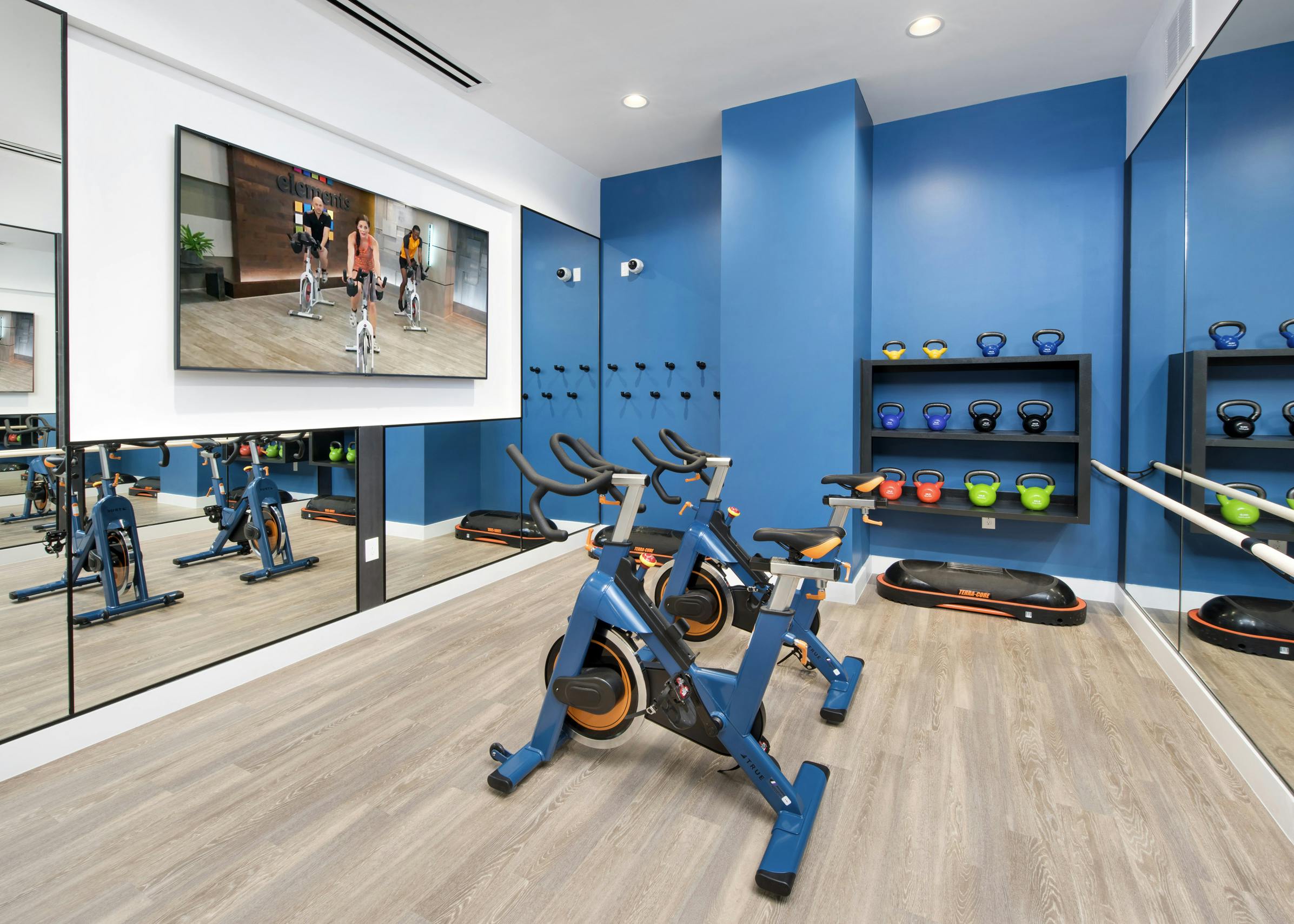 Interior of fitness center at AMLI Decatur with fitness on demand on large screen tv, spin bikes and kettle bells