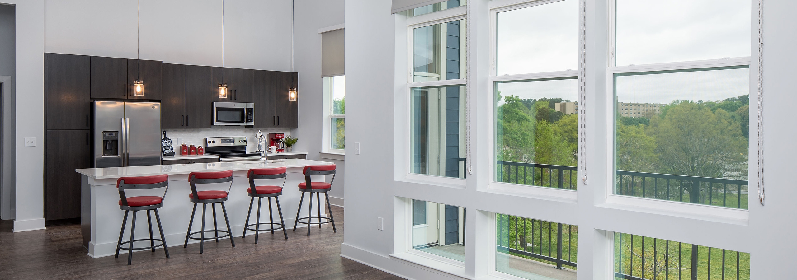 AMLI Decatur island kitchen with wood floors and large windows with a door leading out to balcony with a bright nature view