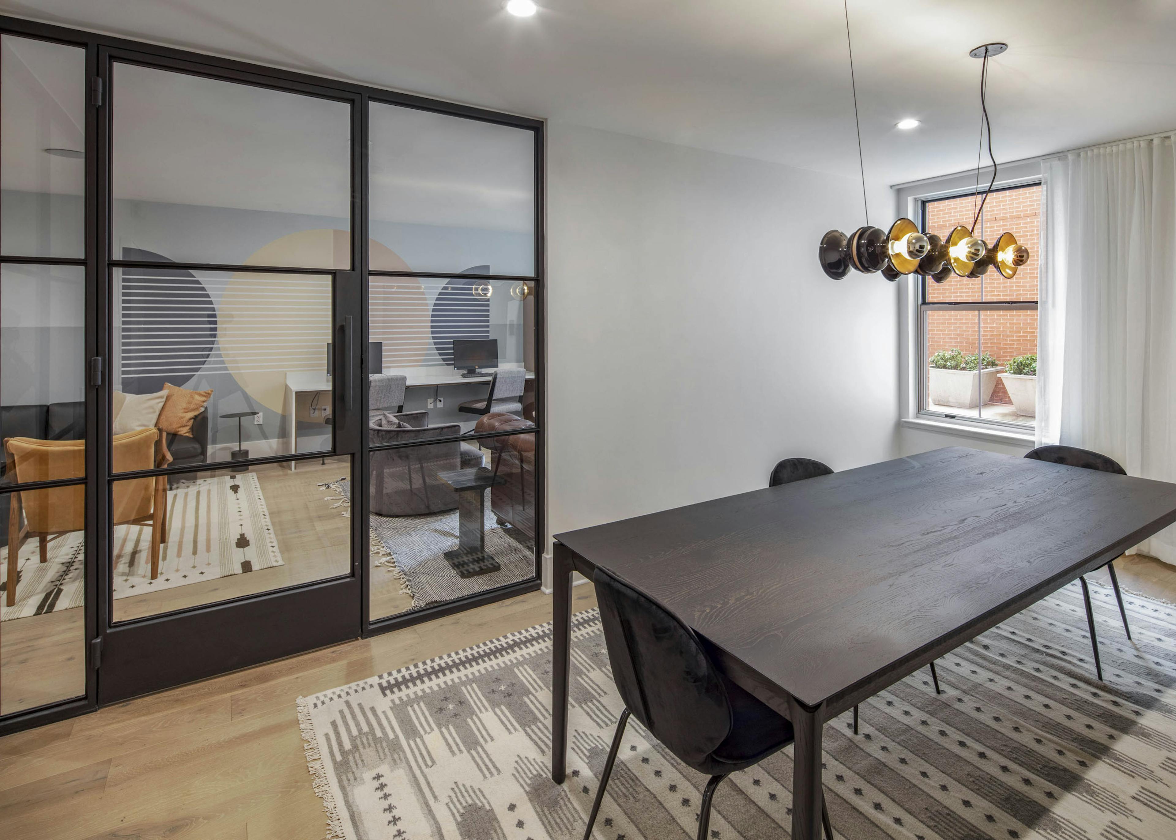 Conference room at AMLI Downtown with a large wooden table with 3 chairs and views to outside and adjacent business center