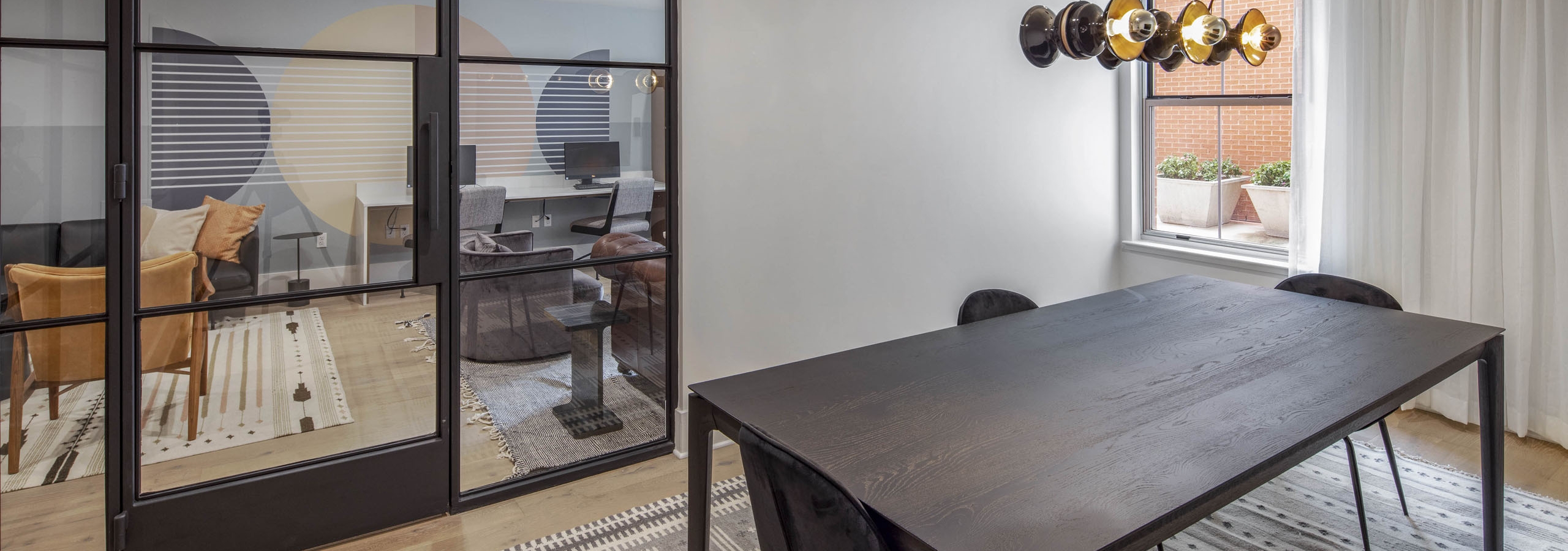 Conference room at AMLI Downtown with a large wooden table with 3 chairs and views to outside and adjacent business center
