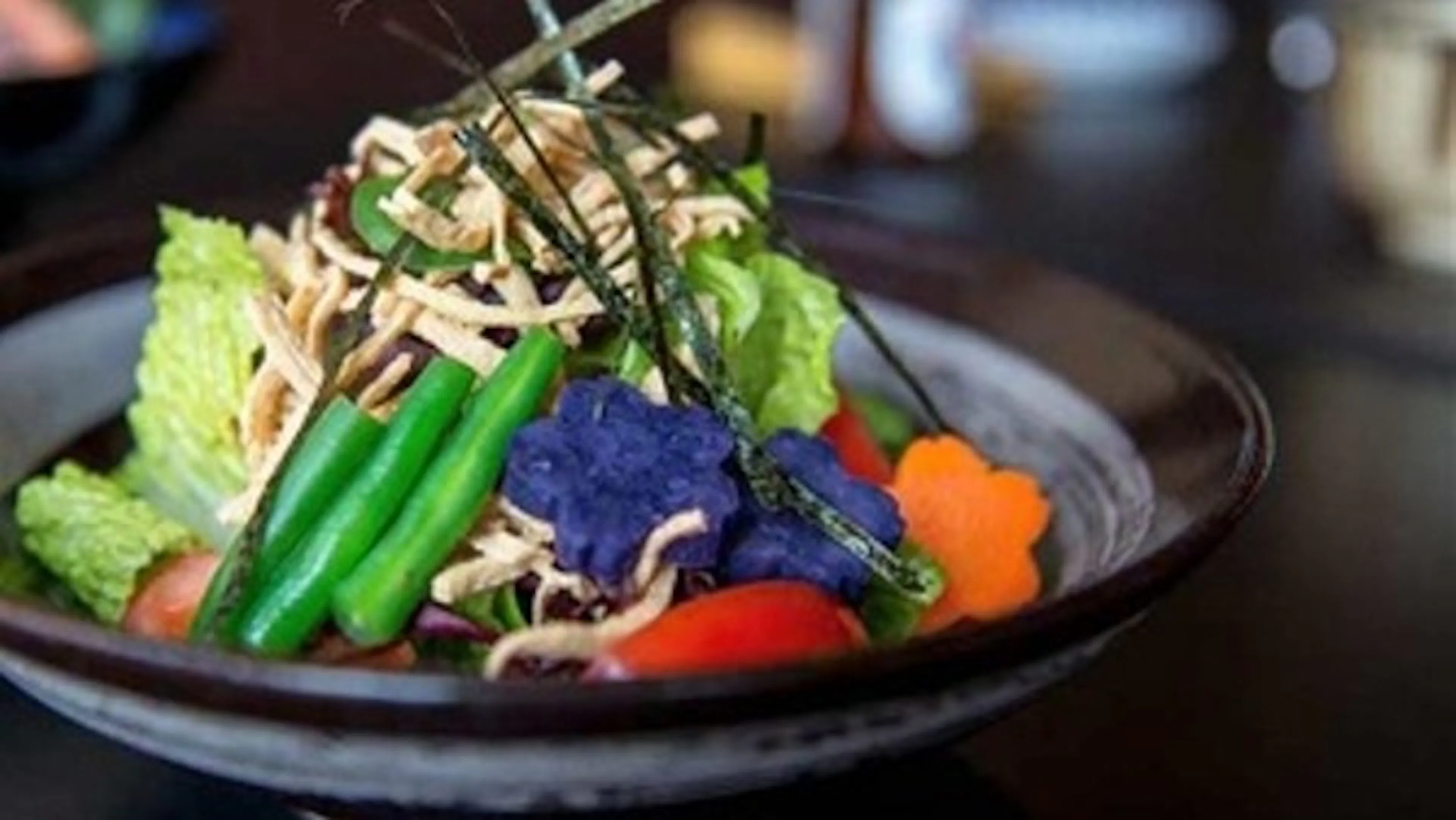 Close-up of a colorful, fresh salad with unique flower-shaped vegetables and crunchy toppings