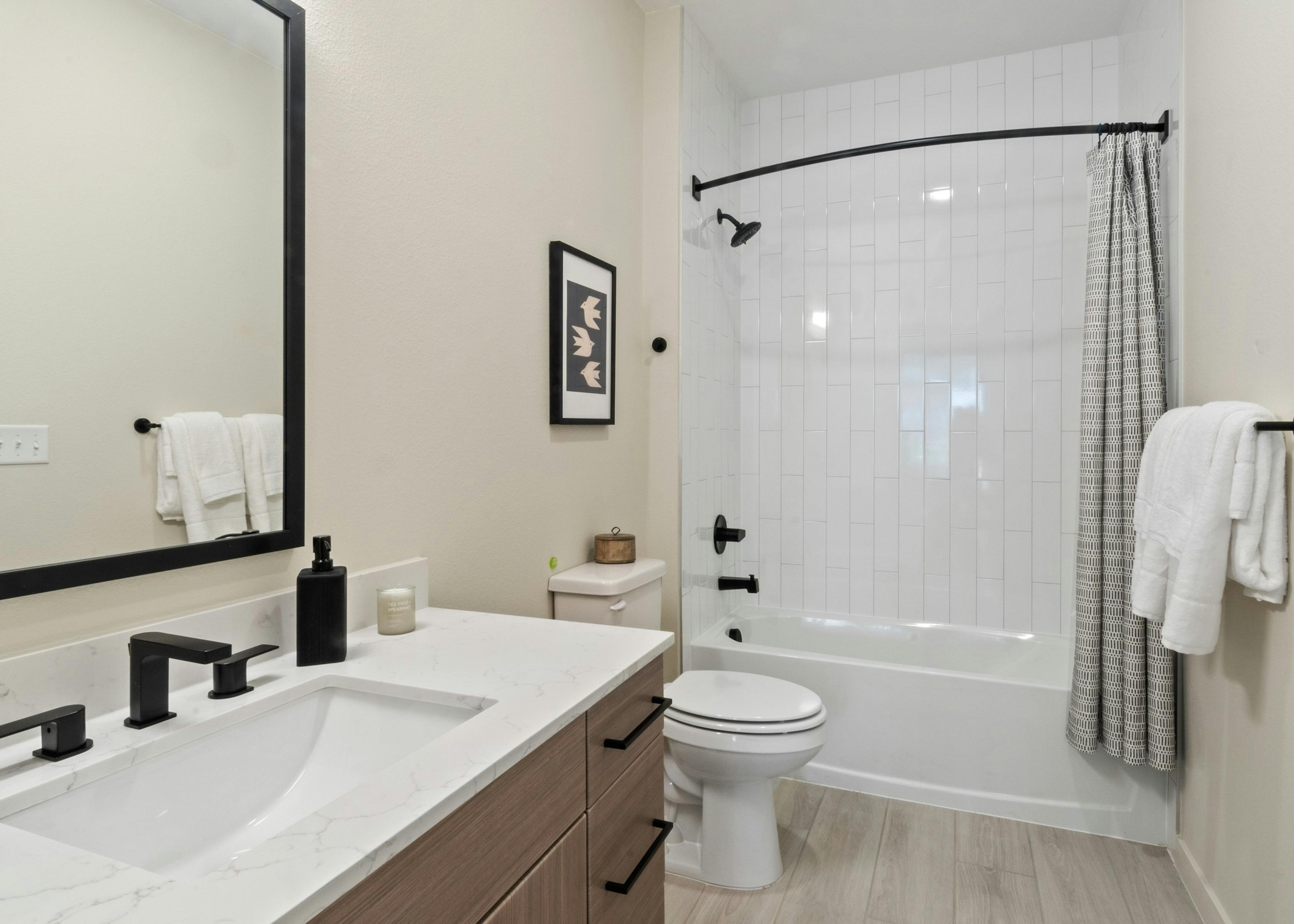 Interior view of a bathroom at AMLI Broadway Park featuring matte black fixtures and a shower with a white tile surround 