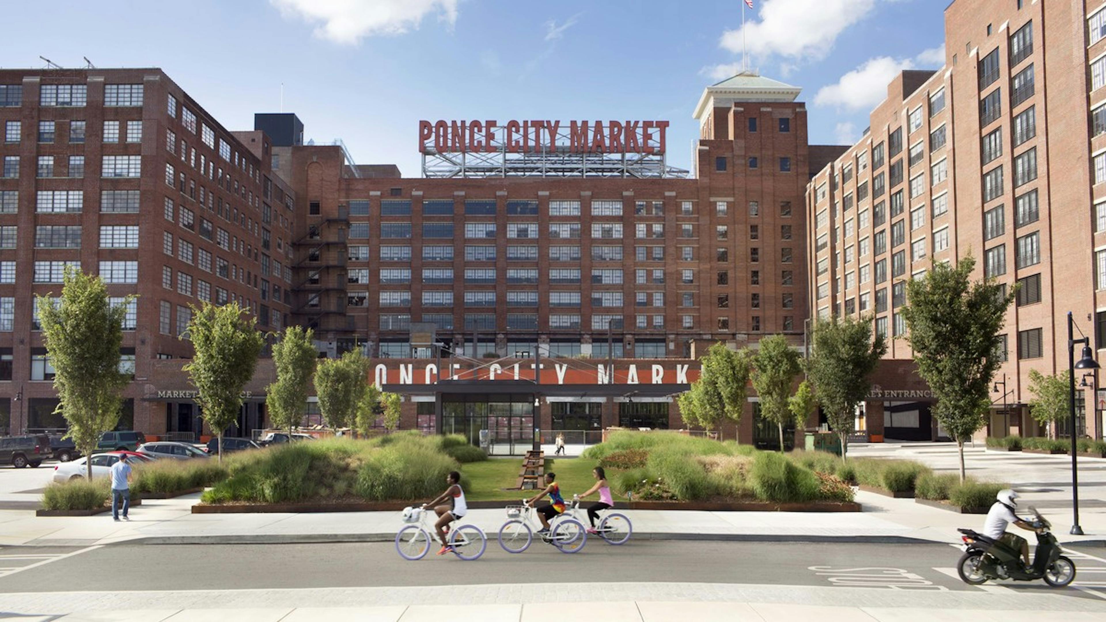 Exterior view of the front of multi story Ponce City Market in Atlanta with bikers passing by on a bright sunny day