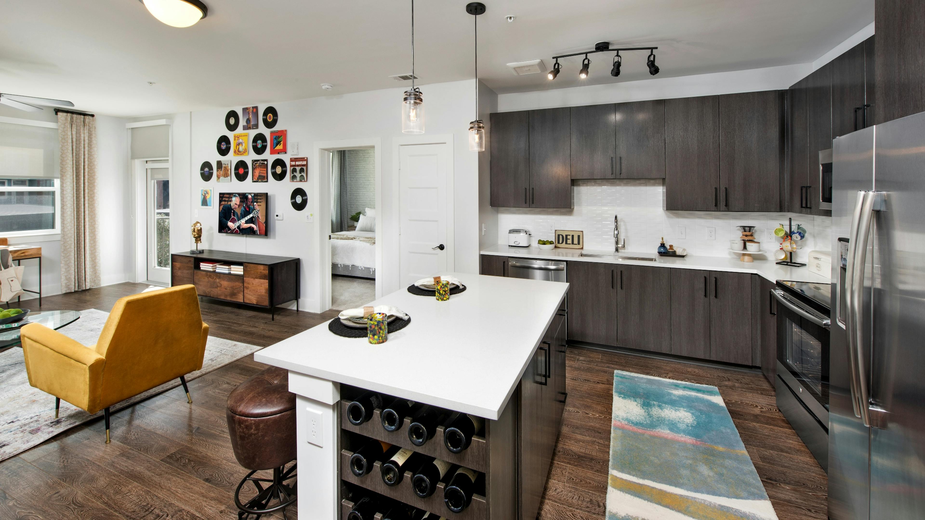Interior view of AMLI Decatur apartment living room and island kitchen with quartz counters and stainless steel appliances