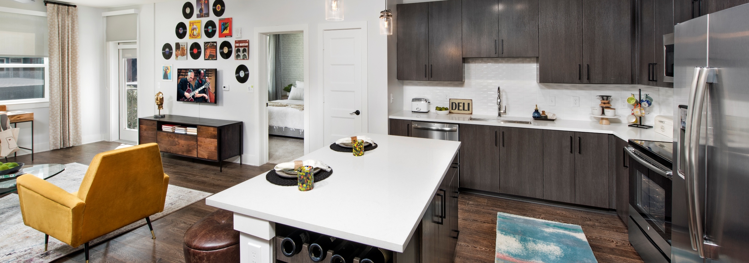 Interior view of AMLI Decatur apartment living room and island kitchen with quartz counters and stainless steel appliances