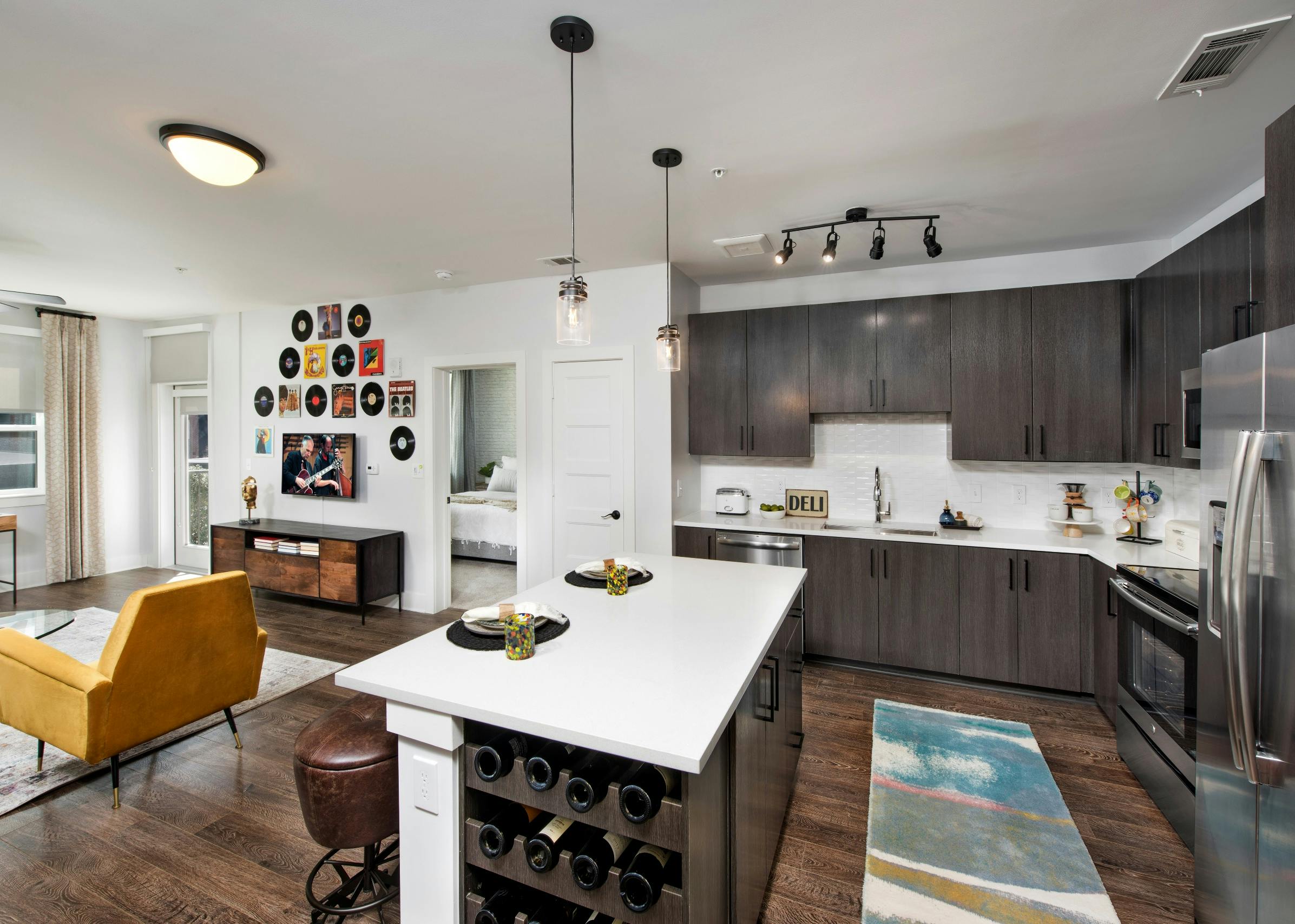 Interior view of AMLI Dectaur apartment living room and island kitchen with stainless steel appliances.