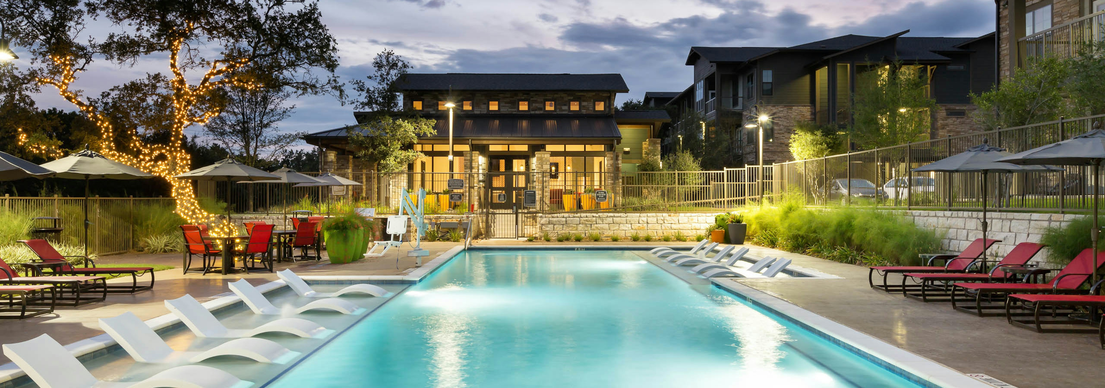 Exterior evening view of AMLI Covered Bridge pool with lounge seating and shaded poolside dining