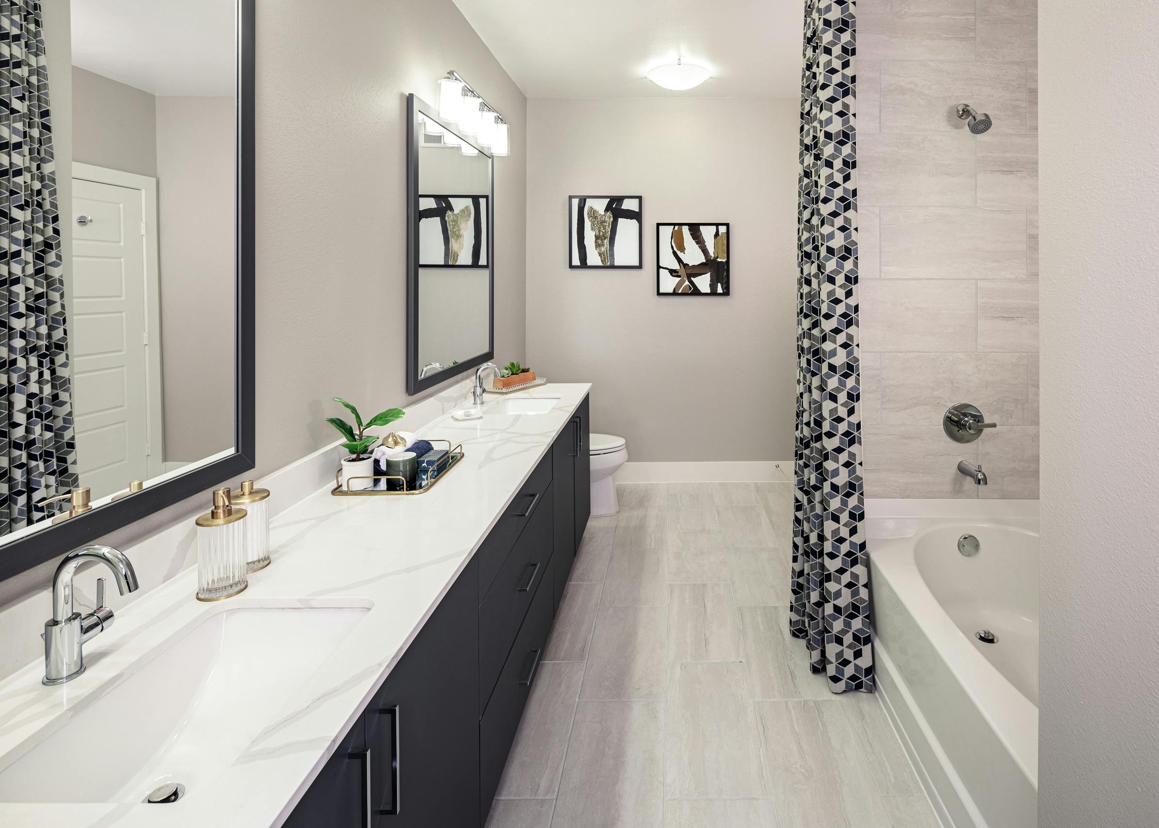AMLI Addison bathroom with dark wood double vanity sink and garden tub with black and white curtains and pale grey tile floor