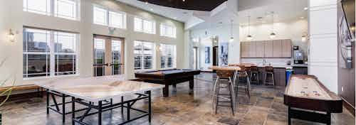 View of the clubroom at AMLI Park Avenue with a shuffle board table and ping pong table and a television and kitchen area
