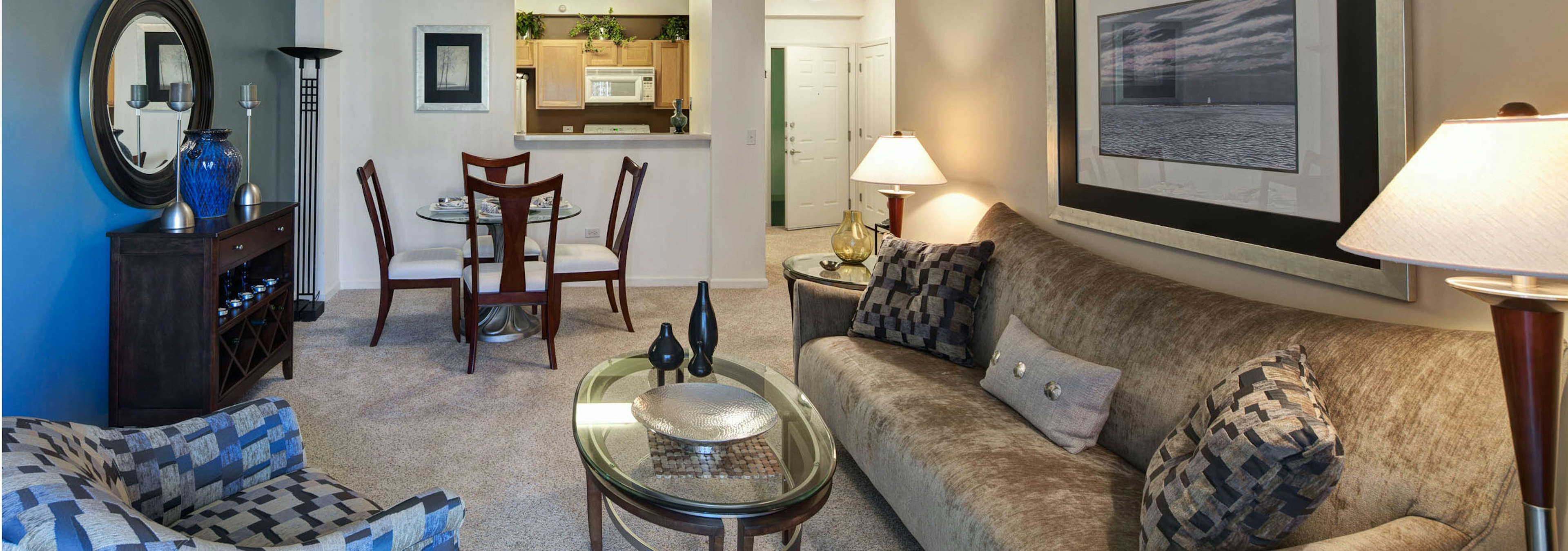 Combined living and dining room at AMLI at Seven Bridges with a dark blue accent wall and a passthrough window to the kitchen