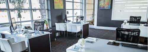 A leasing office at AMLI Arista apartments with several desks and chairs with computers as well as floor to ceiling windows