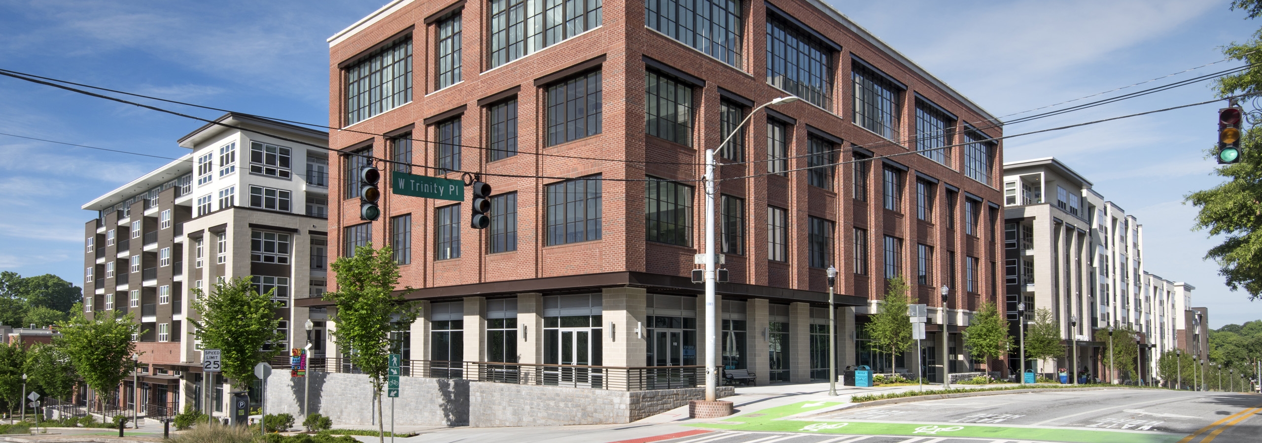 Daytime exterior view of AMLI Decatur apartments with brick façade and Trinity Avenue sign and street in foreground