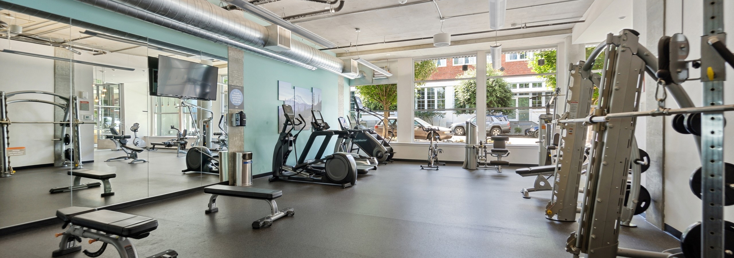 Interior of the fitness center at AMLI South Lake Union with treadmills and weight machines and wall of windows