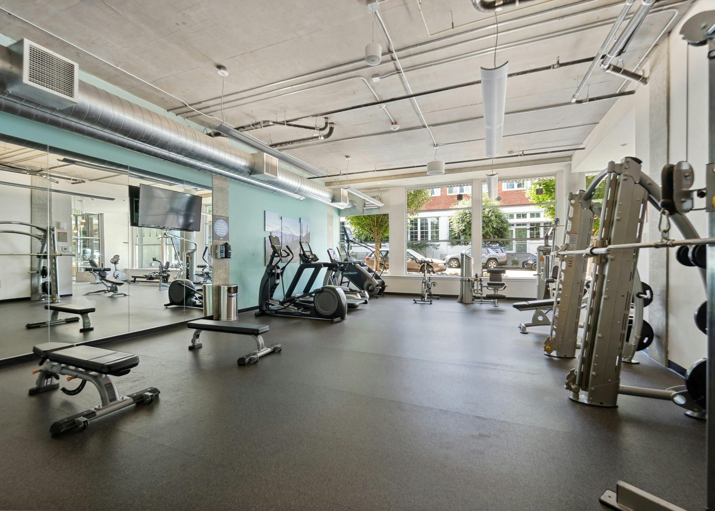 Interior of the fitness center at AMLI South Lake Union with treadmills and weight machines and wall of windows