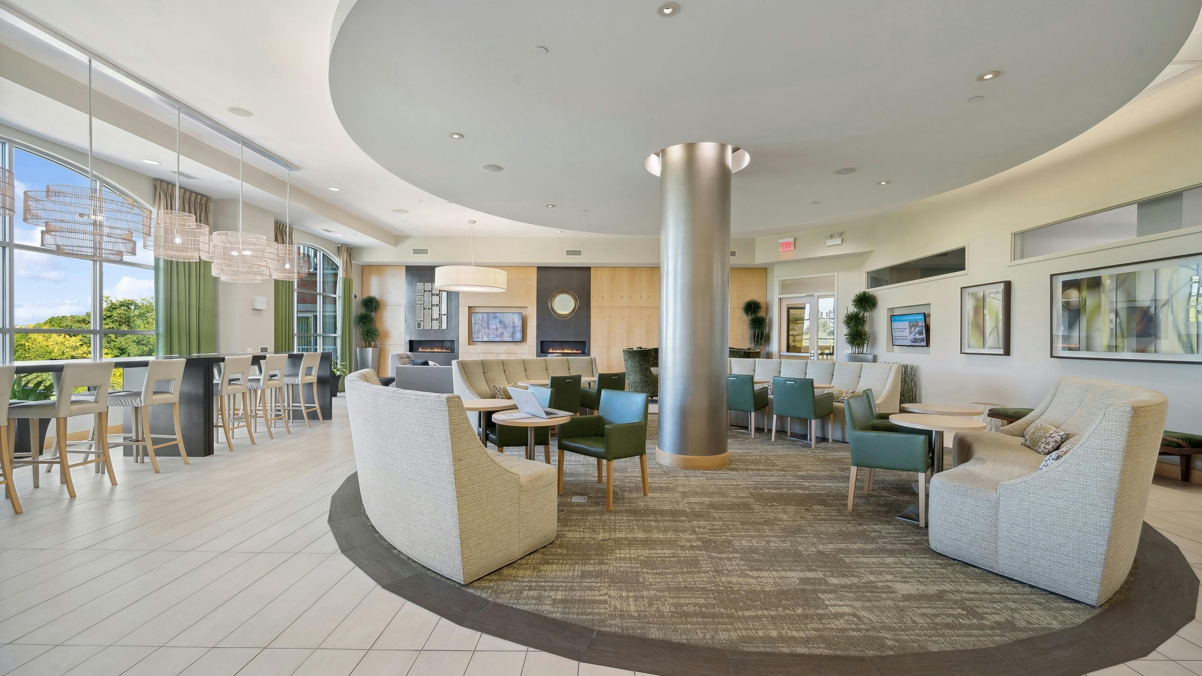 AMLI Evanston resident lounge with couches and other seating options surrounding a silver pillar and along window wall
