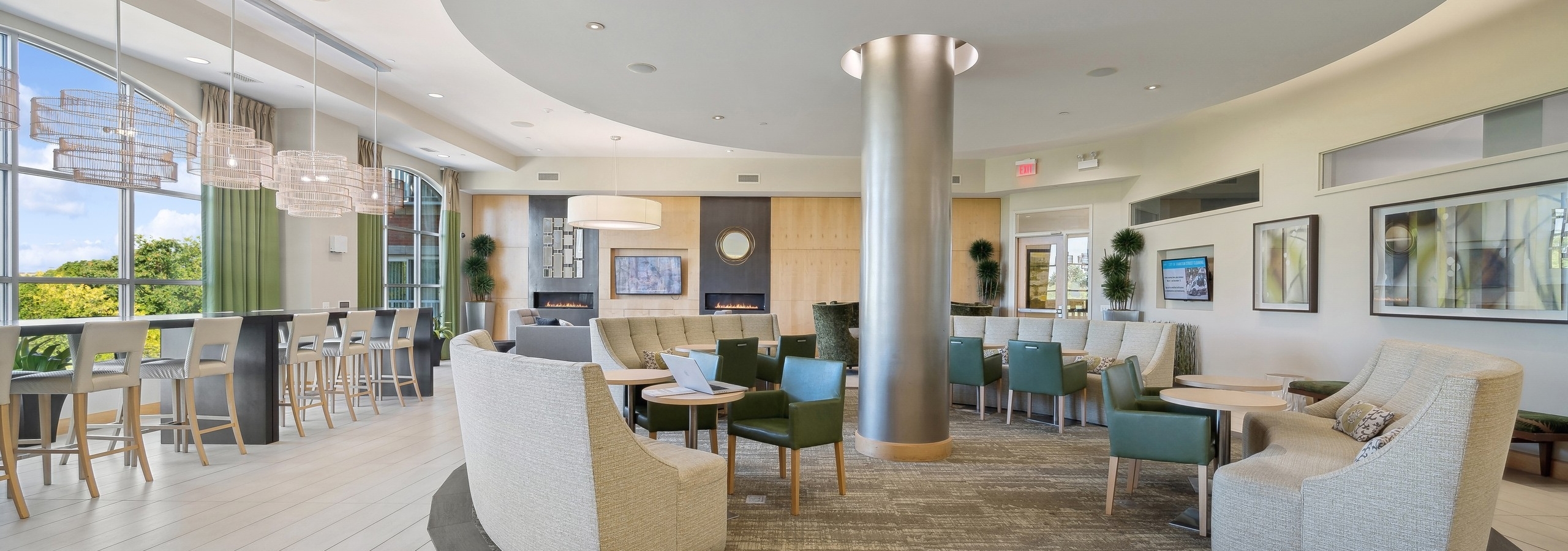 AMLI Evanston resident lounge with couches and other seating options surrounding a silver pillar and along window wall