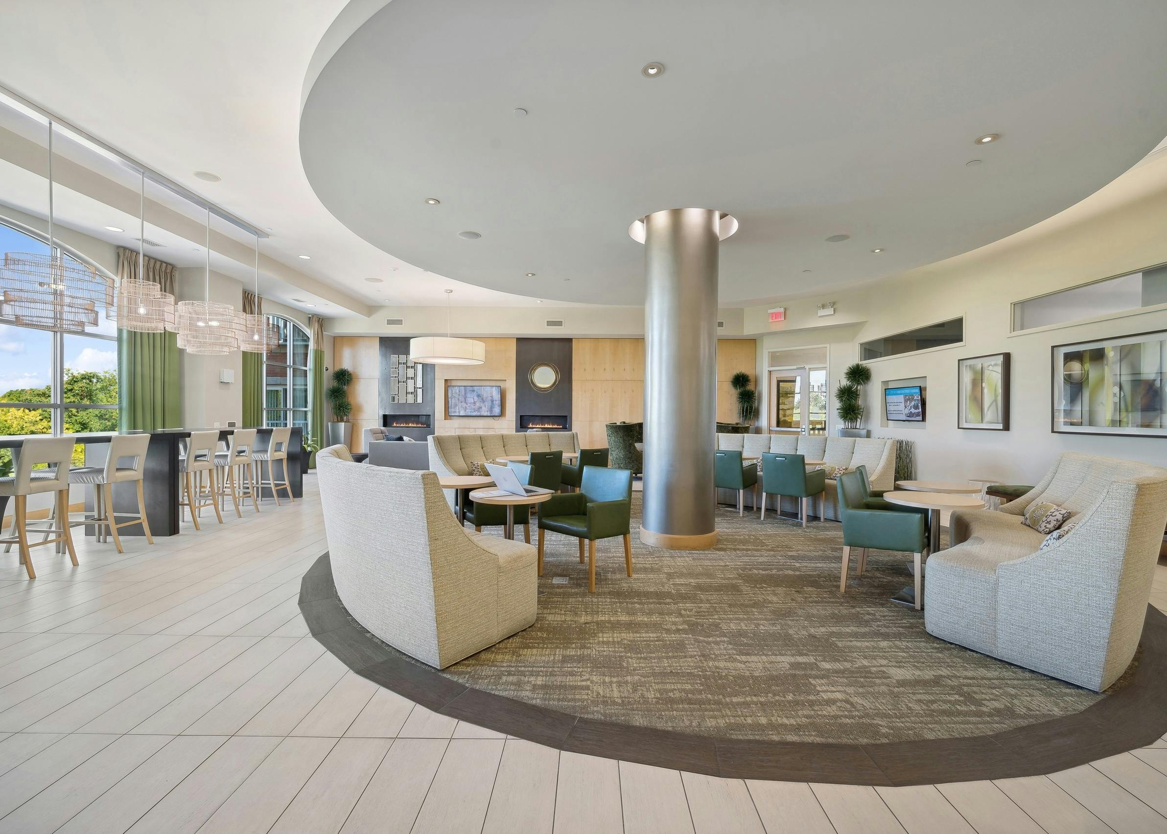 AMLI Evanston resident lounge with couches and other seating options surrounding a silver pillar and along window wall