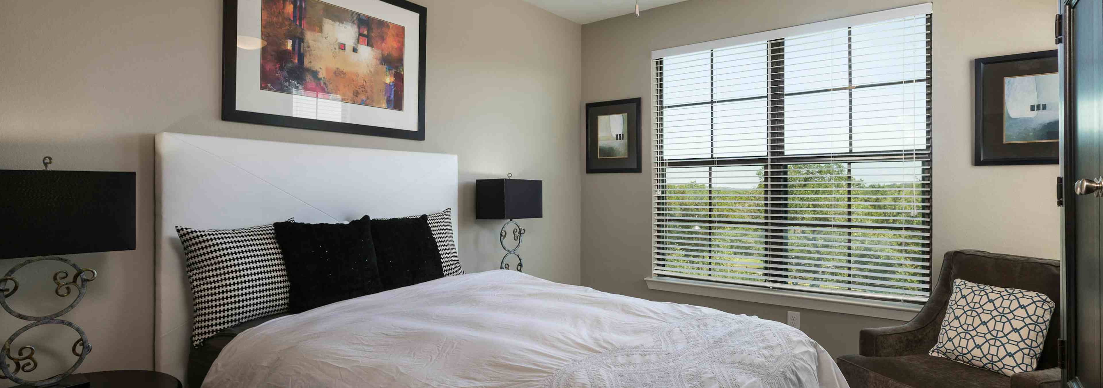 A daytime interior view of AMLI Covered Bridge bedroom with a view of the surrounding Austin Hill Country