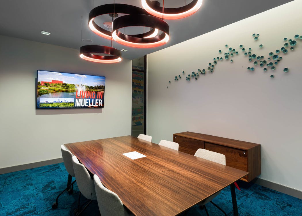Interior view of conference room at AMLI on Aldrich with large wooden desk and a flat screen TV hanging on neutral wall