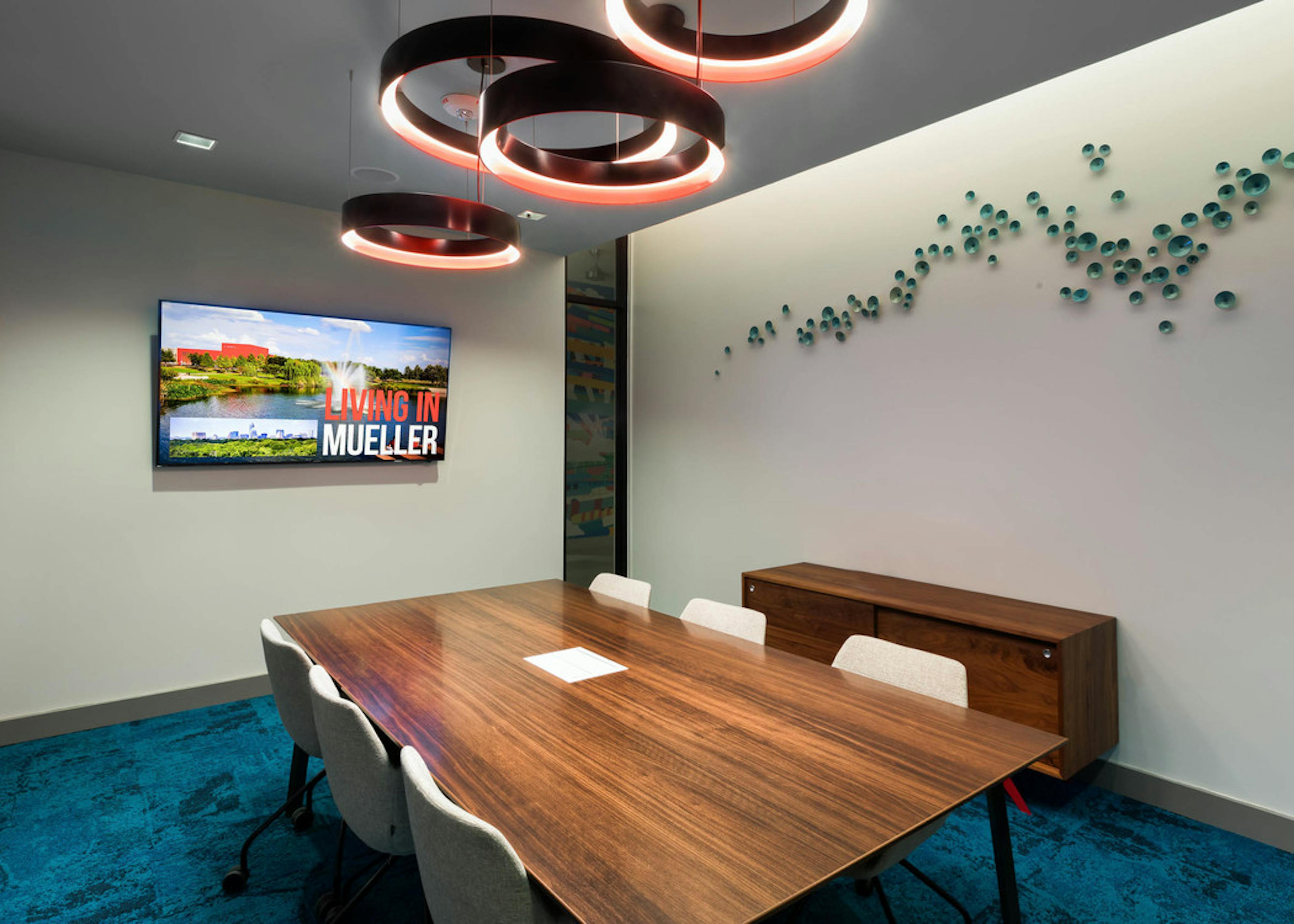 Interior view of conference room at AMLI on Aldrich with large wooden desk and a flat screen TV hanging on neutral wall