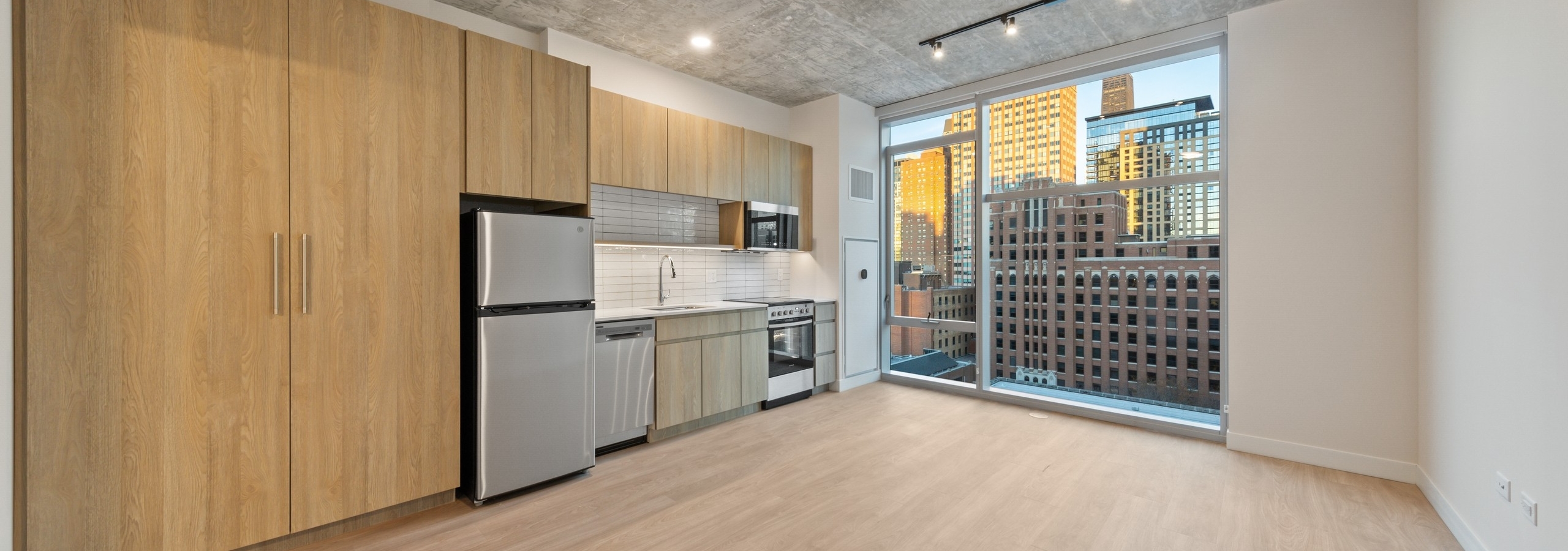 AMLI 808 apartment kitchen with modern cabinetry and spacious pantry doors with light floors and tall windows with city view