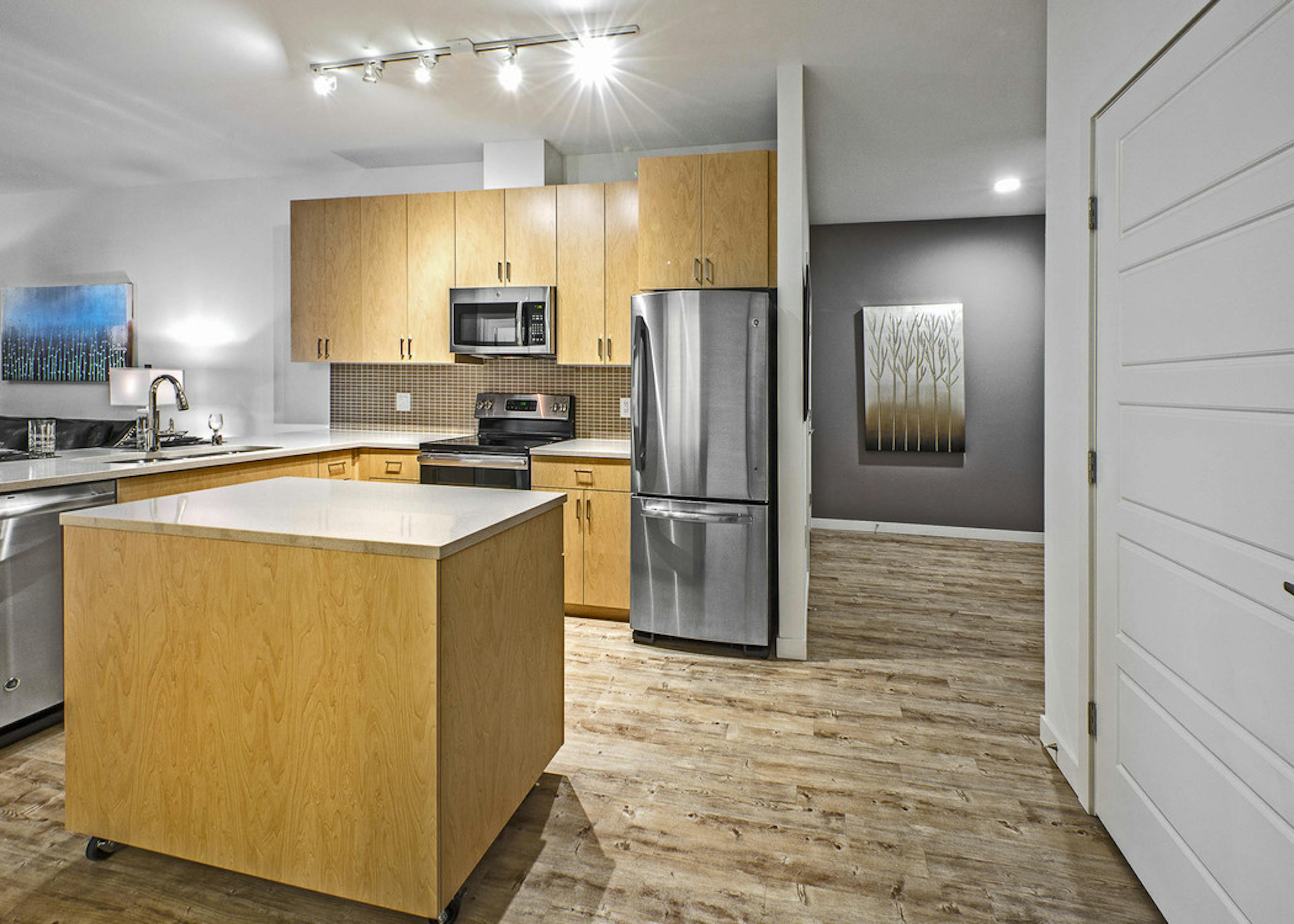 Interior AMLI Wallingford apartment kitchen with island and white quartz countertops and stainless steel appliances 