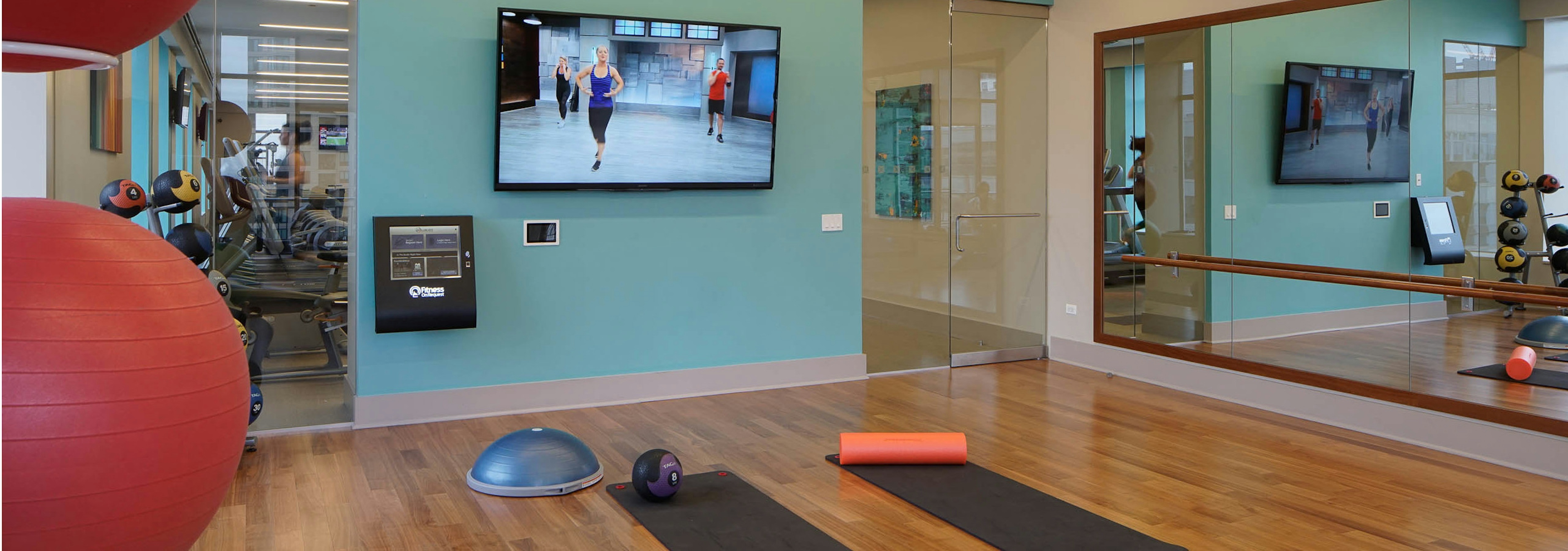 Yoga studio at AMLI River North with a flat screen TV showing an instruction video and two yoga mats laying on the floor