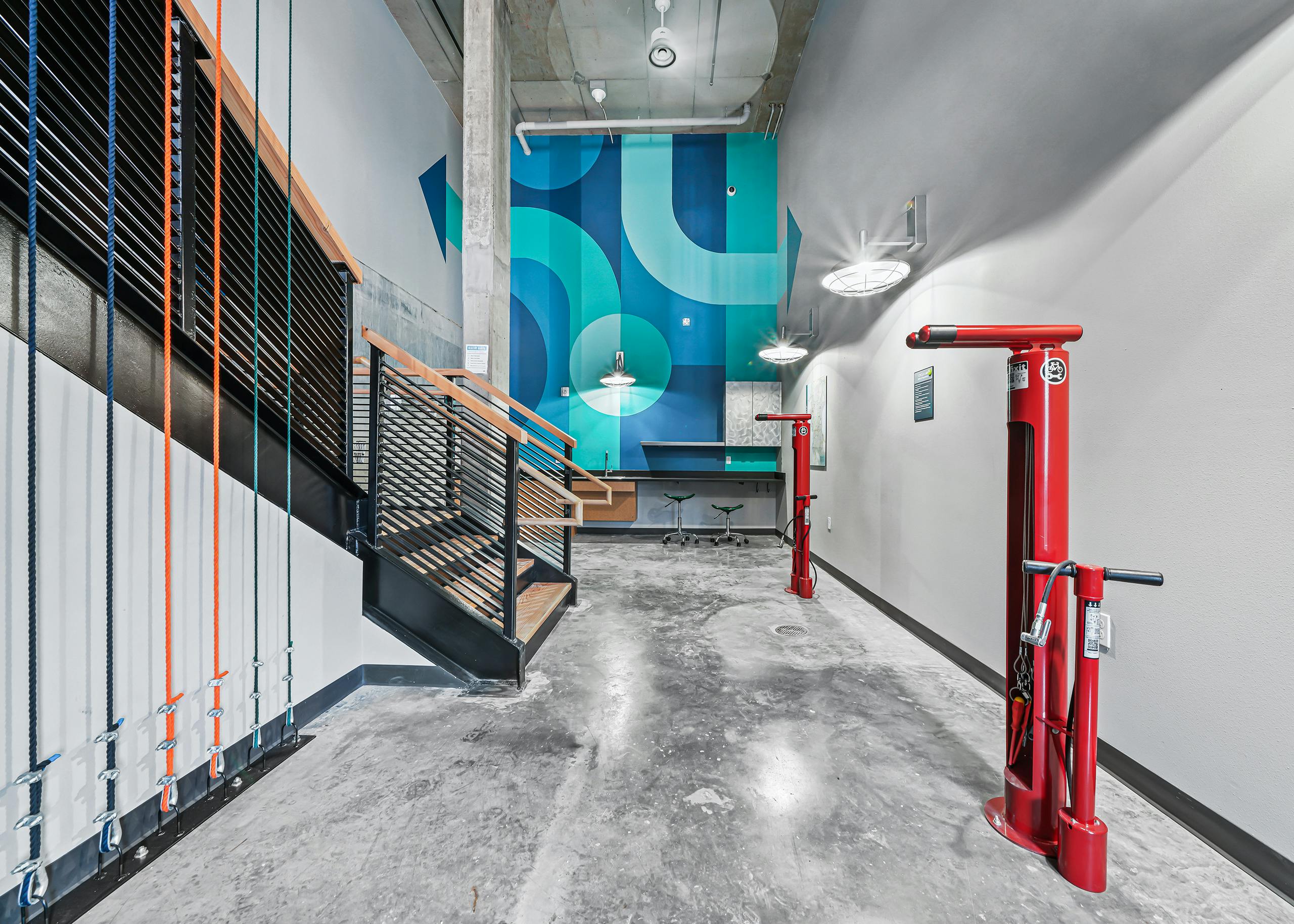 AMLI Spring District bike repair room with gray concrete floor and bright blue accent wall with red air pump stations