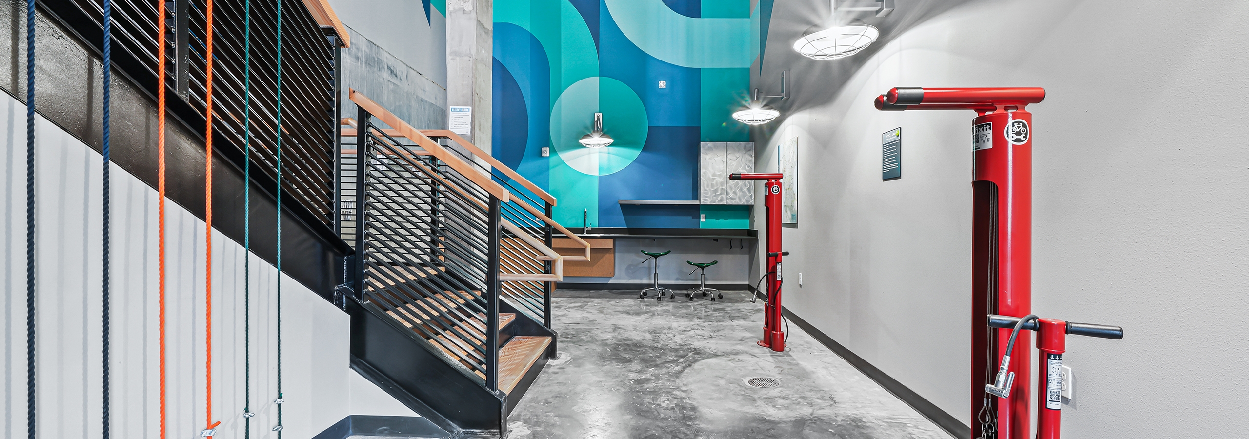 AMLI Spring District bike repair room with gray concrete floor and bright blue accent wall with red air pump stations