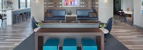 AMLI 3464 clubroom dark wood table in front of blue booth seats and a long white counter with barstools in the background
